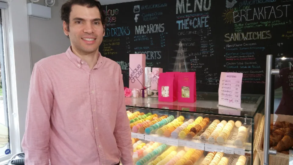 A man in front of a macaron counter.