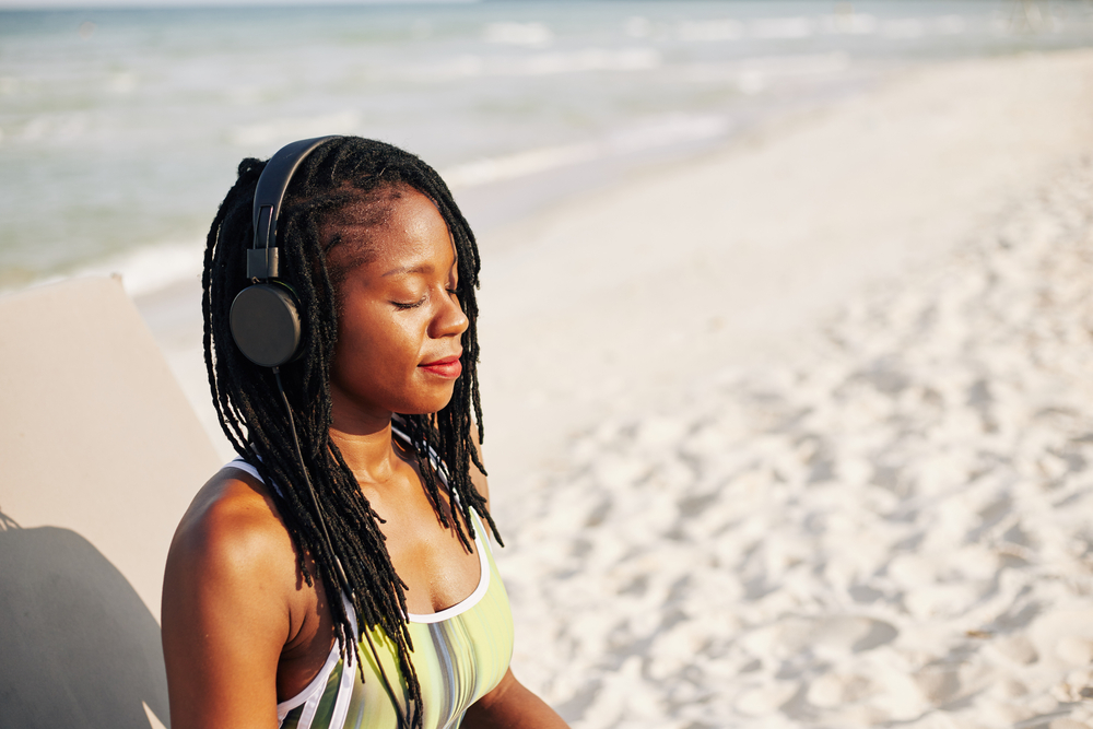How to meditate: woman on the beach with headphones
