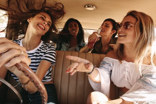 Group of women driving a car and singing along to music