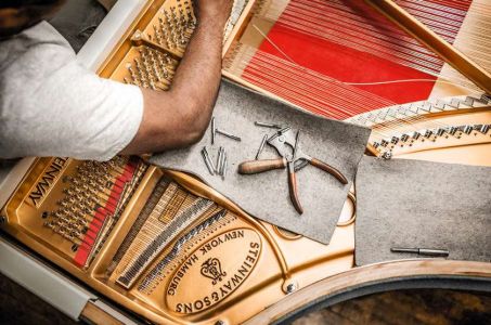 Fixing the strings of a piano.  Each instrument is made up of around 12,000 parts and more than 80% of the making is still done by hand.