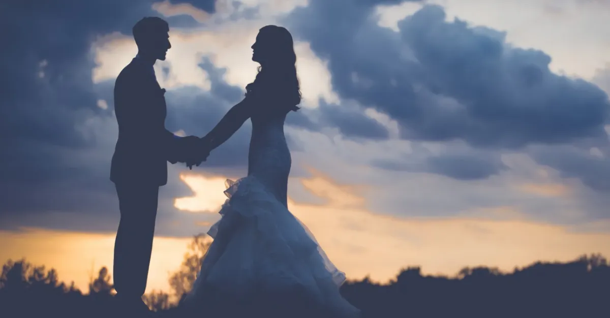two silhouettes of brides on a background of the setting sun with clouds